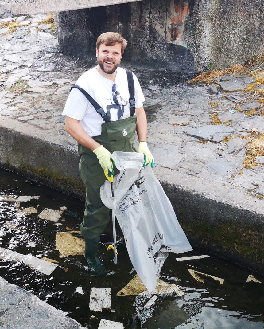 Cllr Alan Edge using a litter picker to clean up refuse from a local waterway.